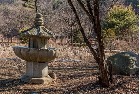 Stone carved pagoda in run down garden on sunny afternoon