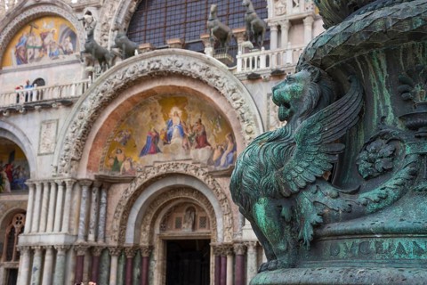 Old street ornament with winged lions and San Marco Basilica in the background, in St. Mark Square,