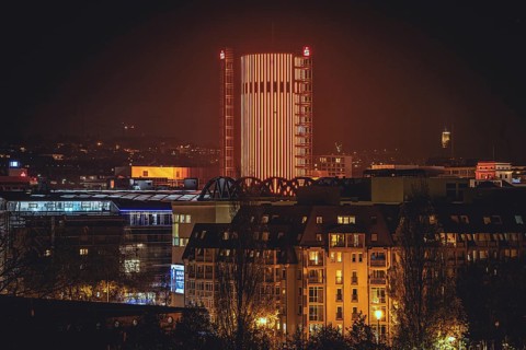 Illuminated skyscraper dominates the cityscape at night under an orange-red sky, Sparkasse Tower,