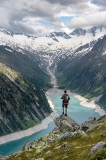 Mountaineer on a rock in front of a mountain panorama, view of Schlegeisspeicher, glaciated rocky