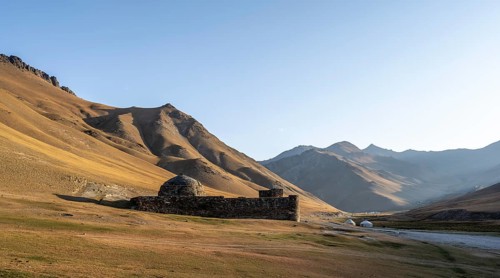 Historic caravanserai Tash Rabat from the 15th century, in the evening light with golden hills and