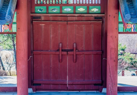 Red wooded gate with tiled roof and colorful, oriental design at a local woodland park in South