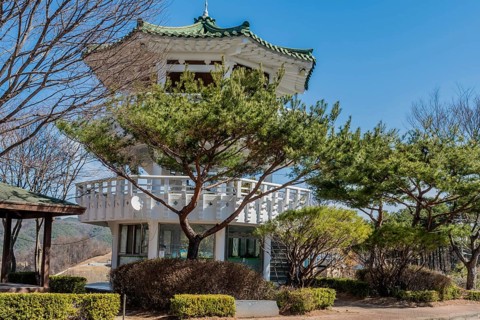 Three story white pagoda under blue sky in roadside park