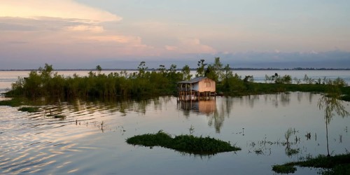 Wooden house on stilts reflecting in a laguna at sunrise, Amazonas state, Brazil, South America