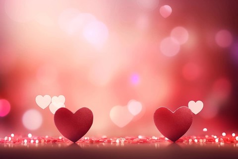A beautiful and romantic background featuring two elegant red hearts against a soft, bokeh light