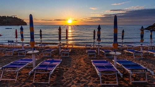Sun loungers and parasols on Straccolignino beach at sunrise, near Capoliveri, Elba, Tuscan