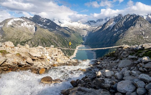 Mountaineers on a suspension bridge over a mountain stream Alelebach, picturesque mountain