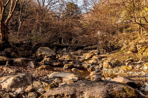 Pebble stack on boulder in dry riverbed in mountain wilderness park