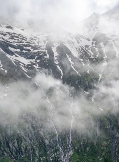 Snow-covered cloudy mountains, mountain streams as waterfalls on a mountain slope, Furtschaglhaus,