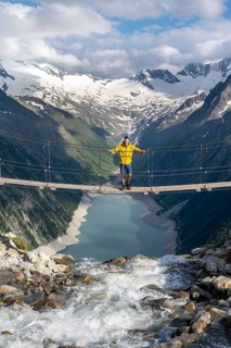 Mountaineers on a suspension bridge over a mountain stream Alelebach, picturesque mountain
