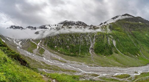 Cloudy valley of Schlegeisgrund with mountain stream, glaciated mountain peaks Hoher Weiszint and