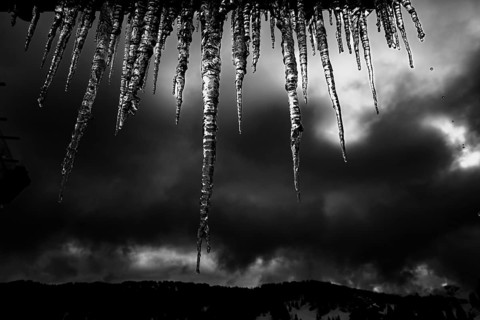 Icicle on gutter in front of dark sky, Balderschwang, Oberallgaeu, Bavaria, Germany, Europe