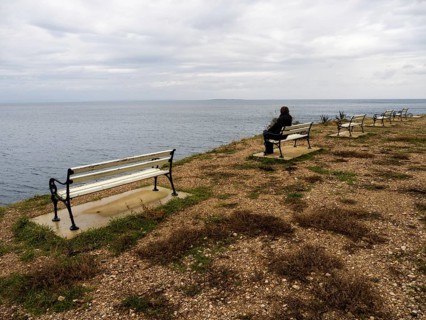 Tourist sitting on a bench and looking out to sea, near Veli Losinj, Kvarner Bay, Croatia, Europe