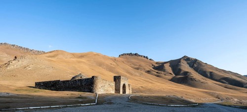 Historic caravanserai Tash Rabat from the 15th century, in the evening light with golden hills,