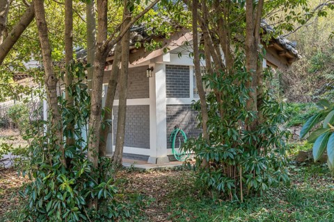 Exterior of public restroom behind copse of trees in nature park