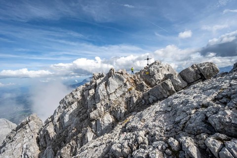 Mountaineer on the rocky summit of the Watzmann Mittelspitze with summit cross, Watzmann crossing,