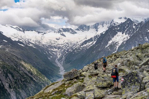 Mountaineer on hiking trail, view of glaciated rocky mountain peaks Hoher Weisszint and Hochfeiler