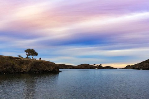 Couple enjoying a picturesque sunset in winter, bay on the Cap de Creus peninsula, Portlligat, Port
