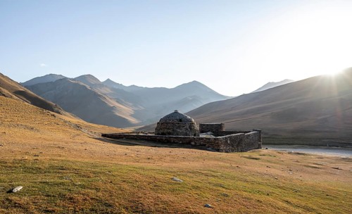 Historic caravanserai Tash Rabat from the 15th century, in the evening light with golden hills,