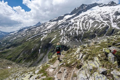 Mountaineer on rocky hiking trail, Berliner Hoehenweg, mountain landscape with snow-covered peak