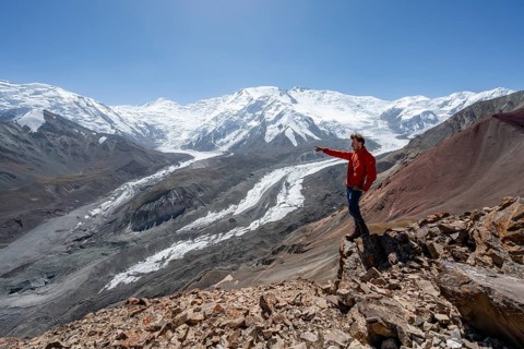 Mountaineer points into the distance, at Traveller's Pass with view of impressive mountain