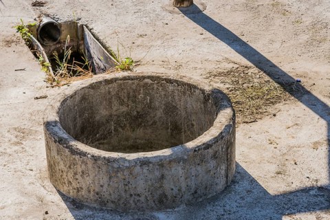 Closeup of concrete irrigation well and drainage pipe used for irrigation of crops in rural