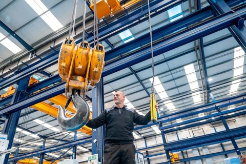 Operator controlling a industrial crane with remote control in a logistics factory