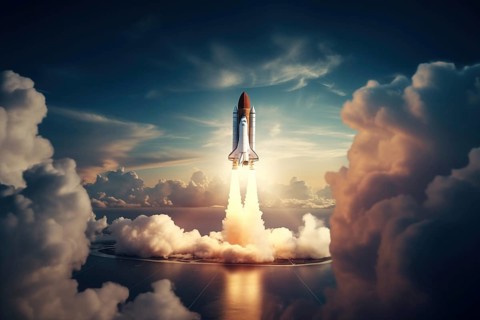 Aerial view of a rocket shuttle carrier launch at sunrise over an ocean coast. The rocket is
