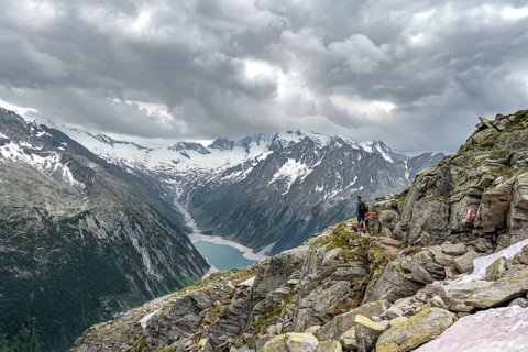 Mountaineer on hiking trail, view of Schlegeisspeicher, glaciated rocky mountain peaks Hoher