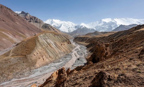 Achik Tash river, Achik Tash valley with rock formations, behind glaciated and snow-covered