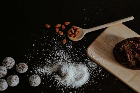 Homemade cookies with almonds and coconut shavings on a dark surface