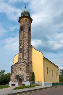 Stone church tower architecture under a cloudy sky next to a pavement, St. Nicholas Church,