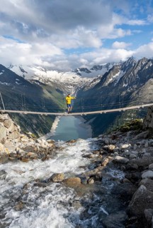 Mountaineers on a suspension bridge over a mountain stream Alelebach, picturesque mountain