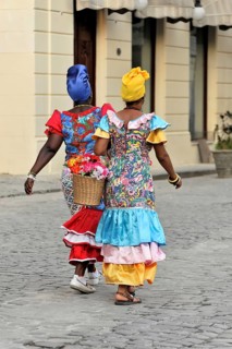 Two Creole women in colourful costumes walking in the centre of Havana, Cuba, Greater Antilles,