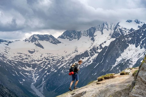 Mountaineer on hiking trail, view of glaciated rocky mountain peaks Hoher Weisszint and Hochfeiler