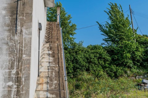 Outside staircase going up to roof of white field in field under blue sky