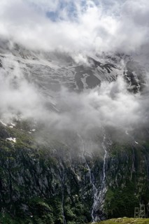 Snow-covered cloudy mountains with summit Hochsteller, mountain streams as waterfalls on a