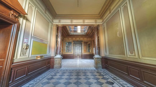 A hallway in a historic building with chequered floor tiles and pillar panelling, Villa Woodstock,