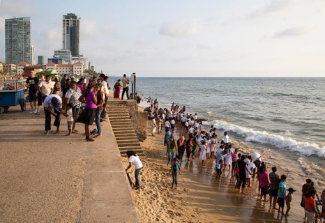 School children paddle in the sea on small sandy beach at Galle Face Green, Colombo, Sri Lanka,