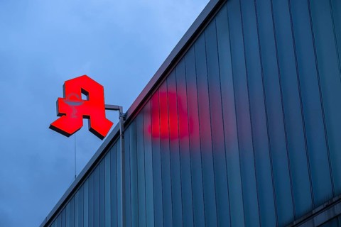 Illuminated pharmacy sign in front of a stormy sky on a facade in Duesseldorf, Germany, Europe