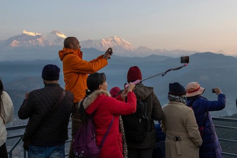 Asian-looking tourists watching and photographing sunrise as well as shooting selfies on the second