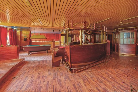 An empty and run-down bar room with a pool table and red curtains, Bad am Park, Lost Place, Essen,