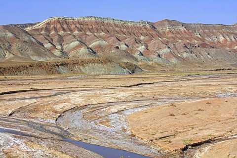 Semi-arid Azerbaijan shrub desert landscape showing mountain with sediment layers and riverbed,