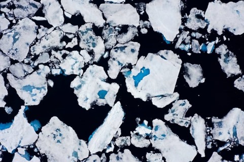 Aerial view over sea ice, drift ice, ice floes with melt ponds containing freshwater in the Arctic