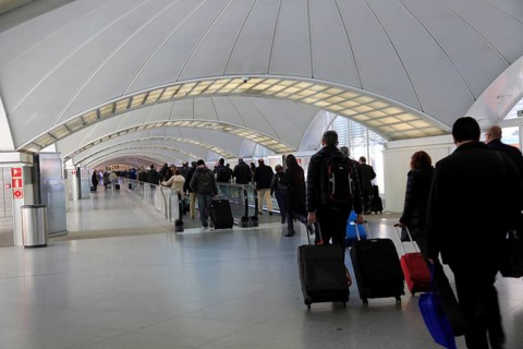 Passengers pulling luggage bags along a bright corridor, Atocha railway station, Madrid, Spain,