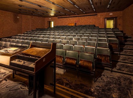 A dark lecture theatre with heavily worn seats and an abandoned lectern, Biotech, abandoned