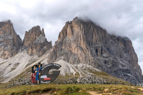 Traditional traditional costume couple advertising sign on the Sella Pass, behind Sassolungo, South
