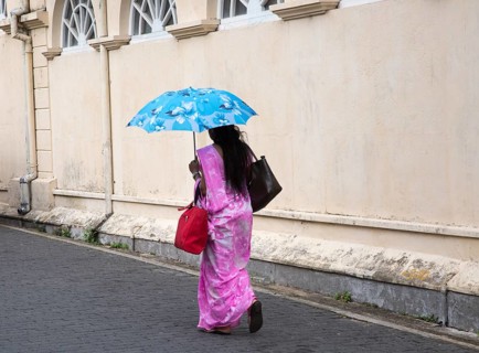 Woman walking with umbrella for shade by the fort walls in the historic town of Galle, Sri Lanka,