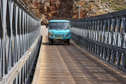 A blue lorry drives over a bridge in mountainous surroundings, Aradena Gorge, Aradena, Sfakia,