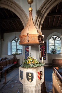 Baptismal font with heraldic shield inside church of Saint Leonard, Horringer, Suffolk, England, UK